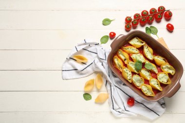 Beyaz ahşap arka planda peynirli, ıspanaklı ve domates soslu koni dolması.