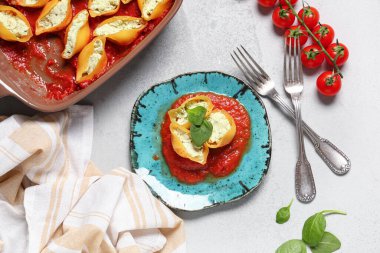 Fırın tabağı ve içi doldurulmuş makarna peynir, ıspanak, domates sosu ve gri arka planda.