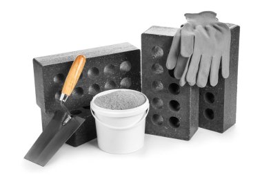 Beyaz arka planda spatula, çimento ve eldivenli tuğlalar