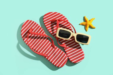 Çizgili parmak arası terlikler, deniz yıldızı ve güneş gözlüğü.
