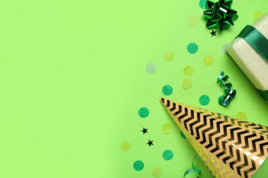 Hediye kutusu, konfeti ve yeşil arka planı olan bir koni partisi şapkası.