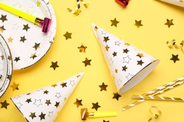 Sarı arka planda pipet, tabak, düdük ve konfeti olan parti şapkaları