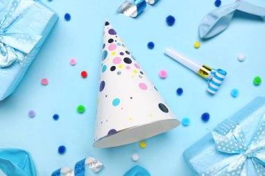 Düdük, hediye kutuları, ponpon topları ve mavi arka planda yılan balıklı koni parti şapkası.