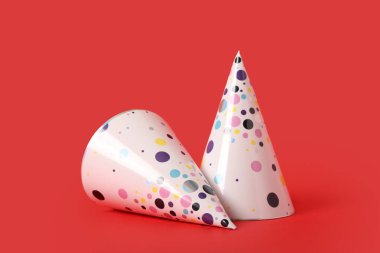 Kırmızı arka planda koni parti şapkaları
