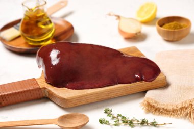 Hafif zemin üzerinde çiğ ciğer ve kekik olan ahşap tahta.