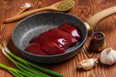 Çiğ ciğer, yeşil soğan, sarımsak ve ahşap zemin üzerinde biber.