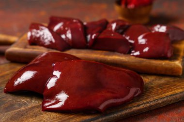 Kırmızı grunge arka planında çiğ karaciğer olan tahta tahtalar.