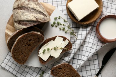 Tereyağlı dilimlenmiş ekmek, kekik ve grunge arka planda bir sürahi süt
