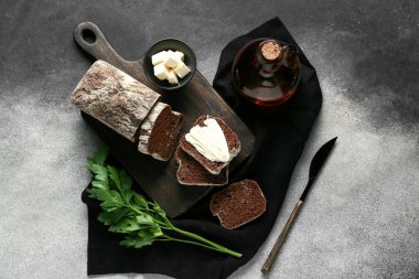 Tereyağlı dilimlenmiş ekmek, maydanoz ve gri grunge arka planda bir sürahi yağ