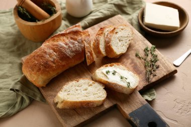 Tereyağlı dilimlenmiş ekmek ve bej arka planda kekik.