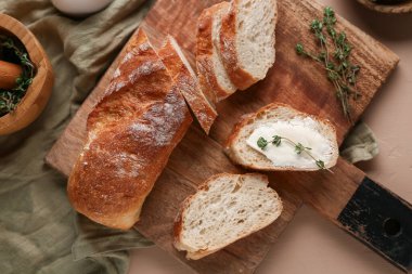 Tereyağlı dilimlenmiş ekmek ve bej arka planda kekik.
