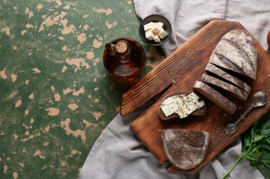 Tereyağlı, maydanozlu dilimlenmiş ekmek, yeşil grunge arka planda bitkiler ve bir sürahi yağ