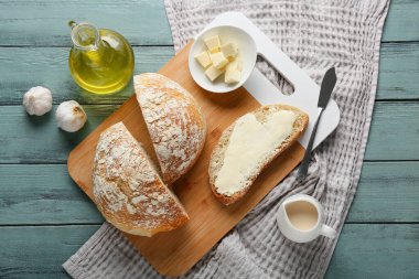 Tereyağlı dilimlenmiş ekmek, sarımsak ve tahta arka planda bir sürahi krema.