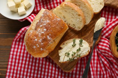 Tahta zemin üzerinde tereyağlı dilimlenmiş ekmek ve kekik.
