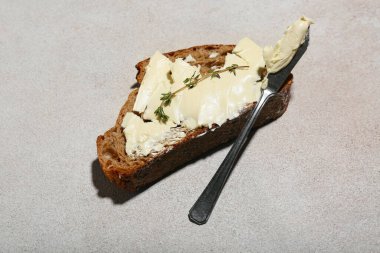 Tereyağlı taze ekmek, kekik ve bıçakla gri grunge arka planda