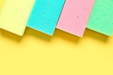 Sarı arkaplanda renkli temizlik süngerleri