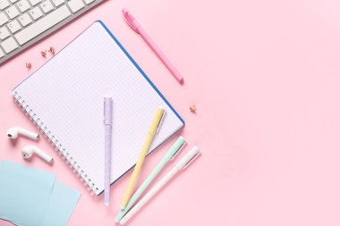 Pembe zemin üzerinde klavye ve kırtasiye malzemesi olan defter