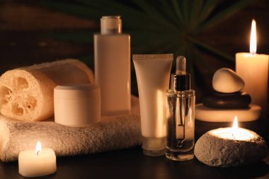 Kaplıca taşları, yanan mumlar, kavanoz ve ahşap zemin üzerinde kozmetik ürünler içeren kompozisyon, yakın plan