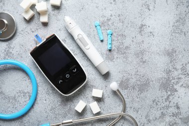 Gri grunge arka planında neşter, steteskop ve şeker küplü glukometre