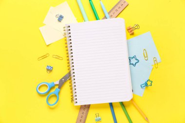 Sarı zemin üzerinde farklı kırtasiye malzemesi olan defter