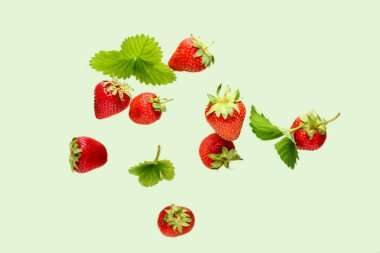 Yeşil arka planda taze çilekler uçuşuyor.