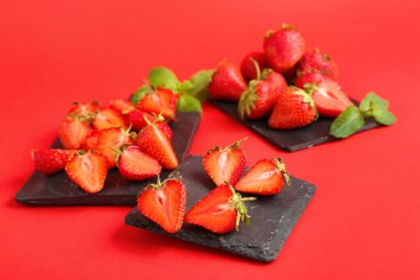 Tatlı çilekli tahtalar ve kırmızı arka planda yapraklar