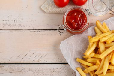 Lezzetli patates kızartması ve hafif ahşap arka planda ketçap kavanoz.