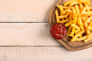 Lezzetli patates kızartması ve hafif ahşap arka planda bir kase ketçap.