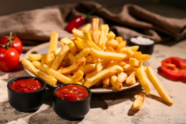 Tabak patates kızartması ve bej grunge masasında ketçap.