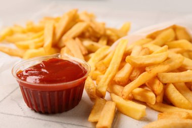 Lezzetli patates kızartması ve arka planda plastik bardak ketçap.