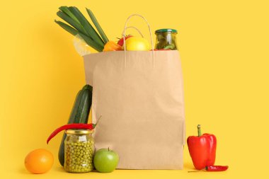 Sarı arka planda sebzeli ve meyveli kağıt torba.