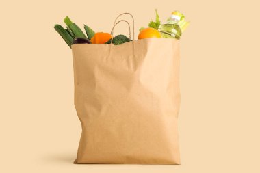 Sebzeli kağıt torba ve bej arka planda bir şişe yağ.