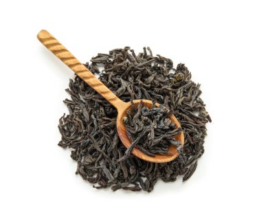 Beyaz arka planda kuru siyah çay yaprakları ile ahşap kaşık.