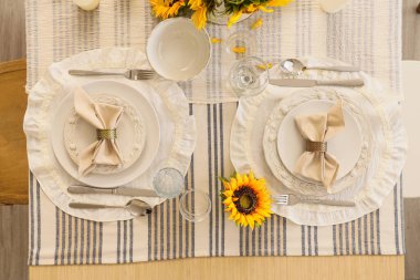 Tabaklarla servis edilen zarif masa, katlanmış peçeteler ve güzel ayçiçekleri, üst manzara.