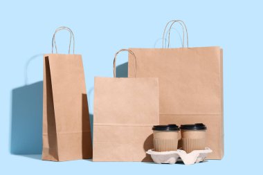 Mavi arka planda kahve fincanları olan farklı kese kağıtları.