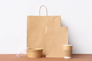 Kahverengi masada beyaz duvarın üzerinde kahve kabı olan kağıt torbalar.