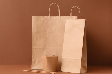 Kahverengi zemin üzerinde yemek çubukları olan kağıt torbalar.