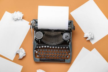 Boş kağıt kağıtları ve kahverengi arka planda buruşuk kağıtları olan klasik daktilo, yakın plan.