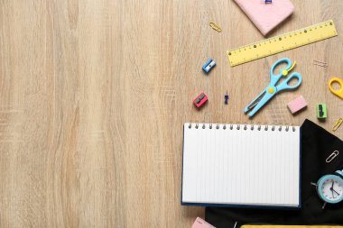 Ahşap arka planda şık okul üniforması olan farklı kırtasiye malzemeleri.