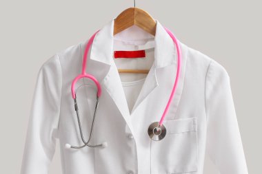 Arka planda steteskop asılı doktor üniforması.