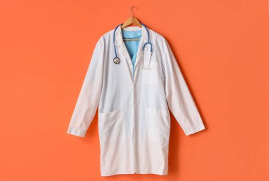 Turuncu arka planda steteskop asılı doktor üniforması.