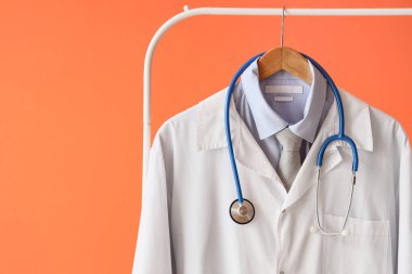 Doktor üniforması. Steteskopu turuncu arka planda asılı. Yakın plan.