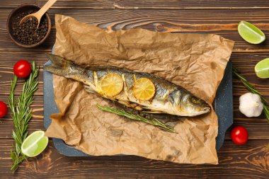 Lezzetli pişmiş deniz kabuğu balığı, domates, biberiye, sarımsak ve limon dilimli ahşap zemin.