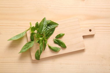 Ahşap arka planda taze fesleğen yapraklarıyla tahta kesme.