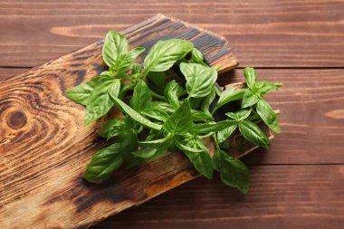 Ahşap arka planda taze fesleğen yapraklarıyla tahta kesme.