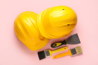 Pembe arka planda fırçalı şapkalar ve macun bıçağı, üst manzara.