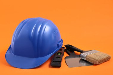 Turuncu arka planda fırça, mala ve ruh seviyeli mavi şapka