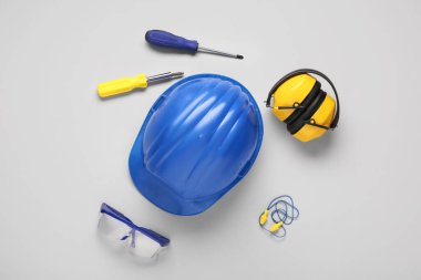 Tornavidalı mavi şapka, güvenlik gözlükleri, işitme koruyucuları ve beyaz arka planda kulak tıkaçları.