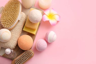 Masaj vücut fırçaları, sabun barları ve pembe arka planda banyo bombaları, yakın plan.