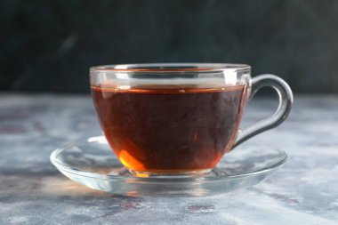 Gri grunge arka planda bir fincan lezzetli siyah çay, yakın plan.